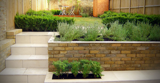 A lawn area with seating surrounded by box hedges and lavendar
