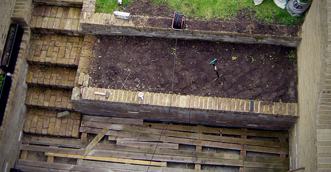 A basement level deck with broken wood and bricks