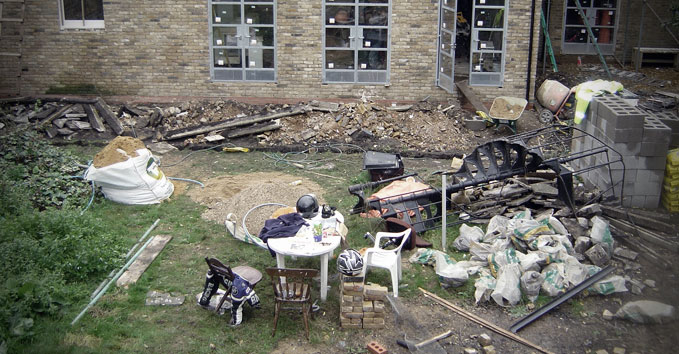 A garden strewn with building materials and weeds